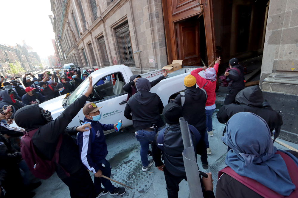 Jóvenes de Ayotzinapa derriban una puerta del Palacio Nacional con López Obrador adentro